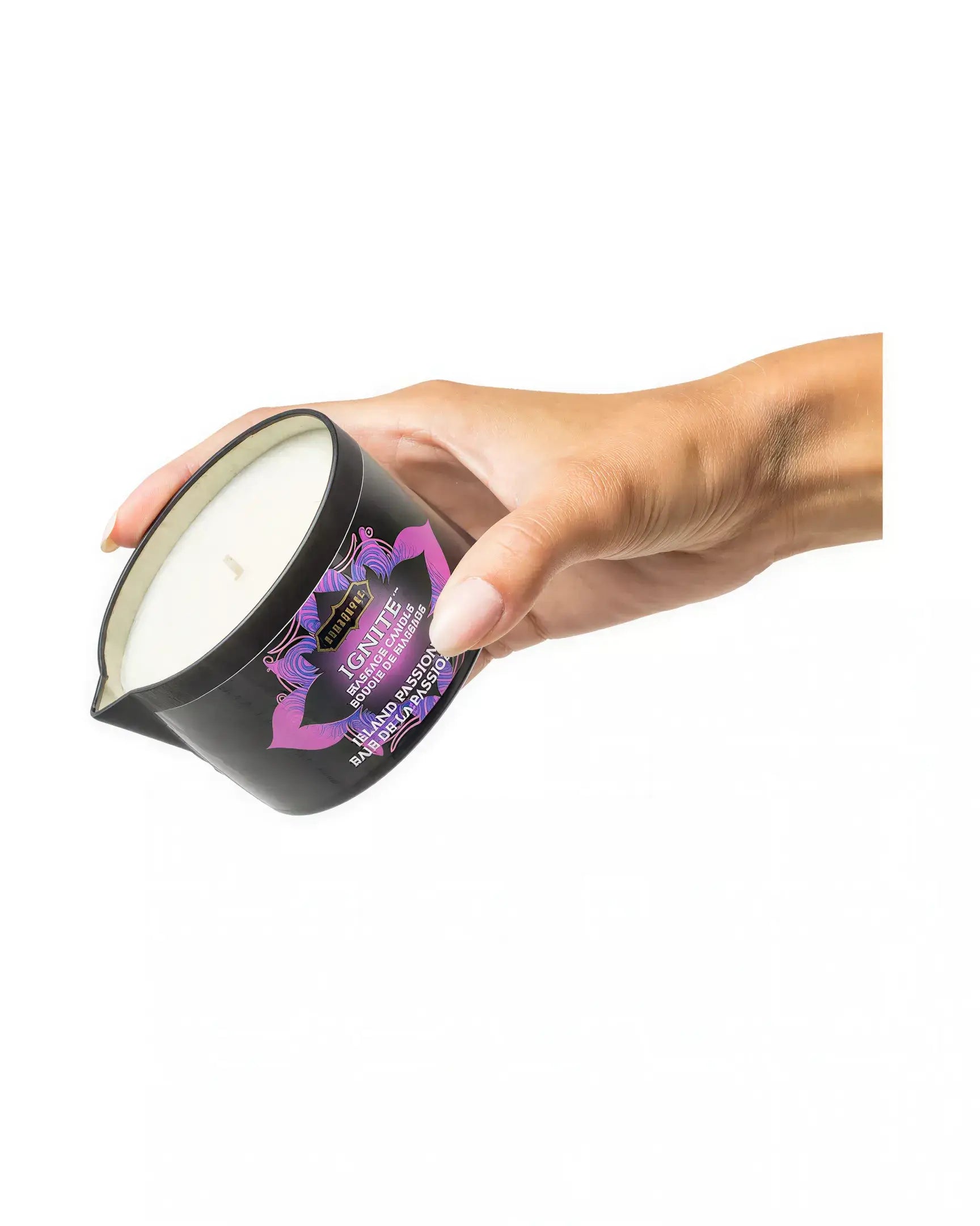 Kama Sutra Island Passion Berry massage candle in a black container, held by a hand, with a white wax top.