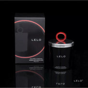 Lelo massage candle in a black container with a red lid, displayed beside its black box packaging.