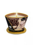 Shunga massage candle in a decorative container with a chocolate scent, featuring a romantic design and lit wick.