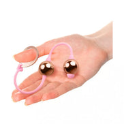 Rocks Off Golden Balls, featuring two bronze-colored balls connected by a pink silicone strap, held in a hand.