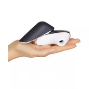 Satisfyer Pro Traveler in a hand, featuring a sleek black and white design with a curved shape for portability.