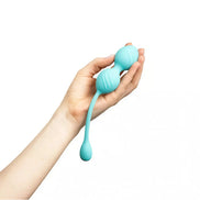 Rechargeable vibrating Kegel ball held in a hand, featuring a smooth turquoise design and a flexible tail.