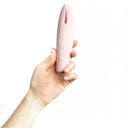 Luxury clit vibrator in soft pink, held in a hand, featuring a sleek design with a tapered tip.