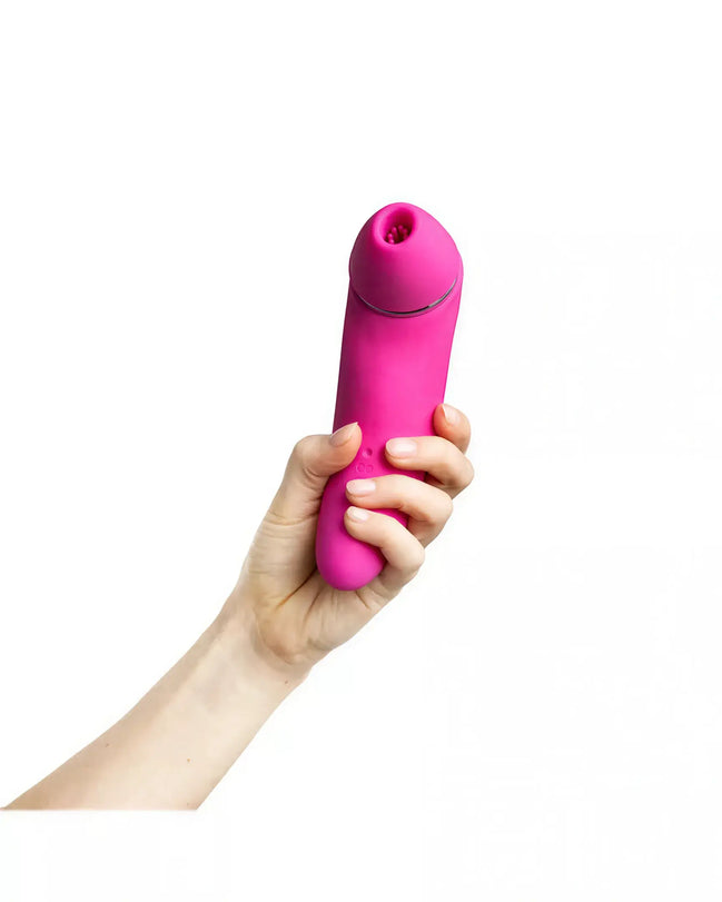 Pink Electra sucking vibrator held in a hand, featuring a rounded tip and smooth silicone texture.