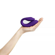 Purple remote-controlled couples vibrator with a sleek design and a white control panel in a hand.