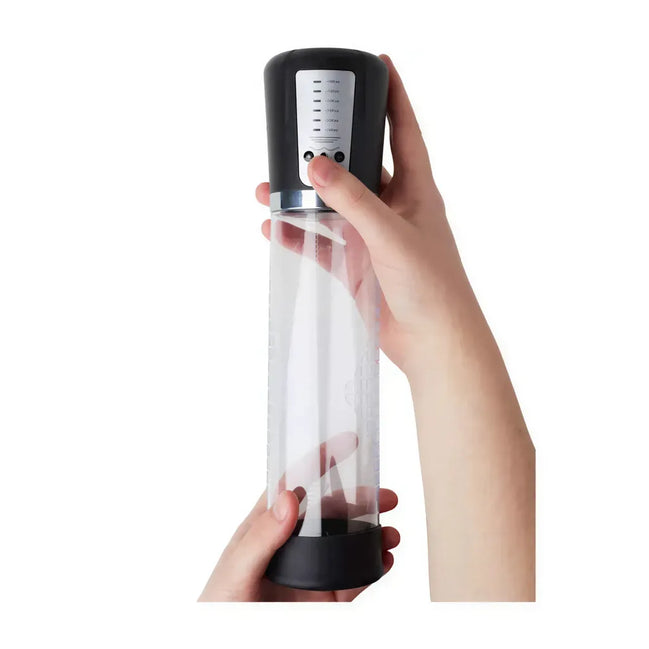 Clear penis pump with a black base, held in one hand, featuring measurement markings and a control panel on top.