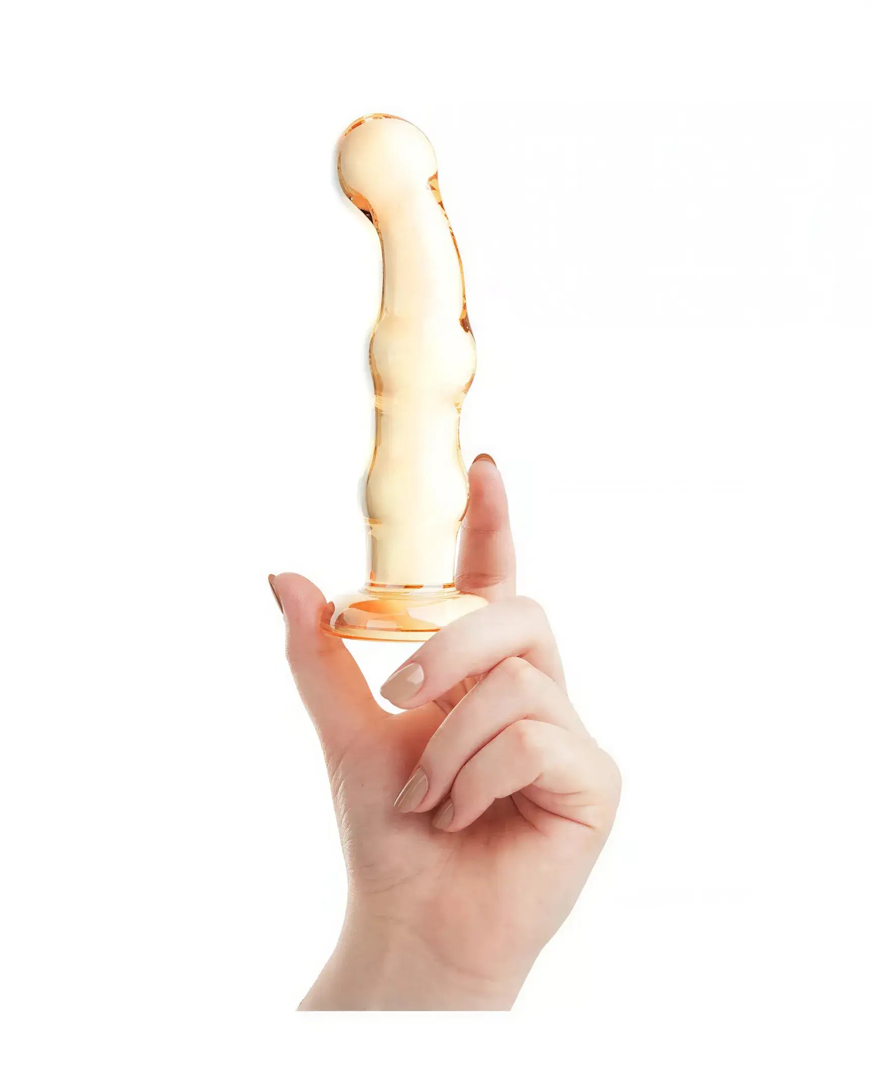 Lucent Soleil glass massager held in a hand, featuring a smooth, curved design in a translucent amber color.