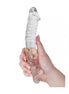 Clear glass massager with a textured body and swirling design, held in a hand for scale.