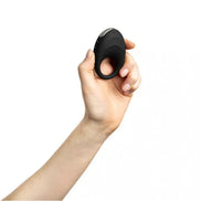 Black vibrating cock ring held in a hand, featuring a smooth surface and ergonomic design.