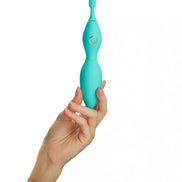 Tanda clitoral vibrator in teal, held in a hand, featuring a textured tip and a central control button.