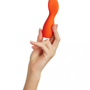 Cato paddle vibrator in bright orange held by a hand, showcasing its ergonomic shape and smooth surface.