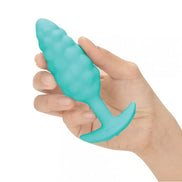 B-Vibe Bump Texture Plug in teal, held in a hand, featuring a textured surface and tapered design.