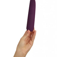 Hand holding a purple silicone vibrator with a textured grip and sleek design.
