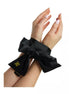Black satin bondage ties with a large bow, secured around wrists, featuring a gold logo tag.