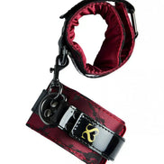 Luxury handcuffs in black and red fabric with a shiny finish, featuring a gold logo and adjustable strap.