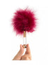 Luxury tickler with a fluffy burgundy feather head and a clear handle, held by a hand.