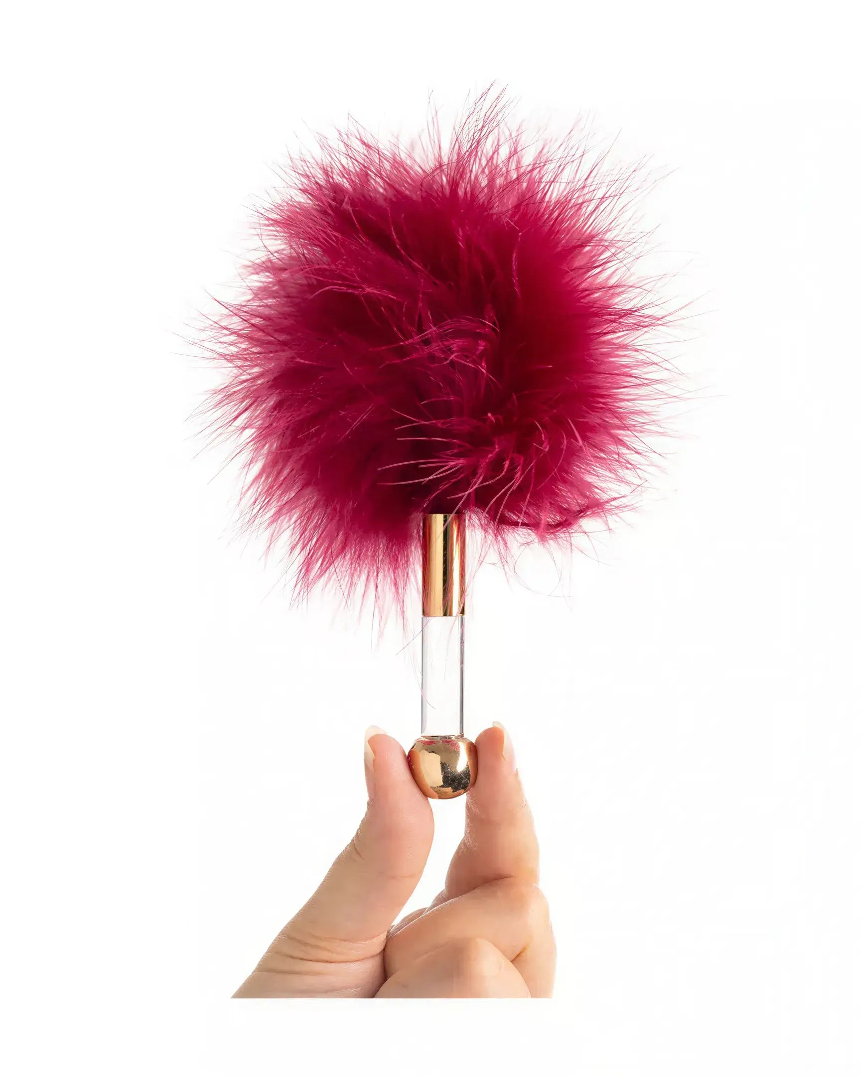 Luxury tickler with a fluffy burgundy feather head and a clear handle, held by a hand.