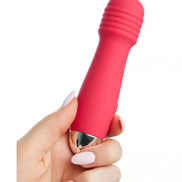 Mini wand vibrator in bright pink silicone with a metallic tip, held in a hand with manicured nails.