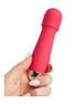 Mini wand vibrator in bright pink silicone with a metallic tip, held in a hand with manicured nails.