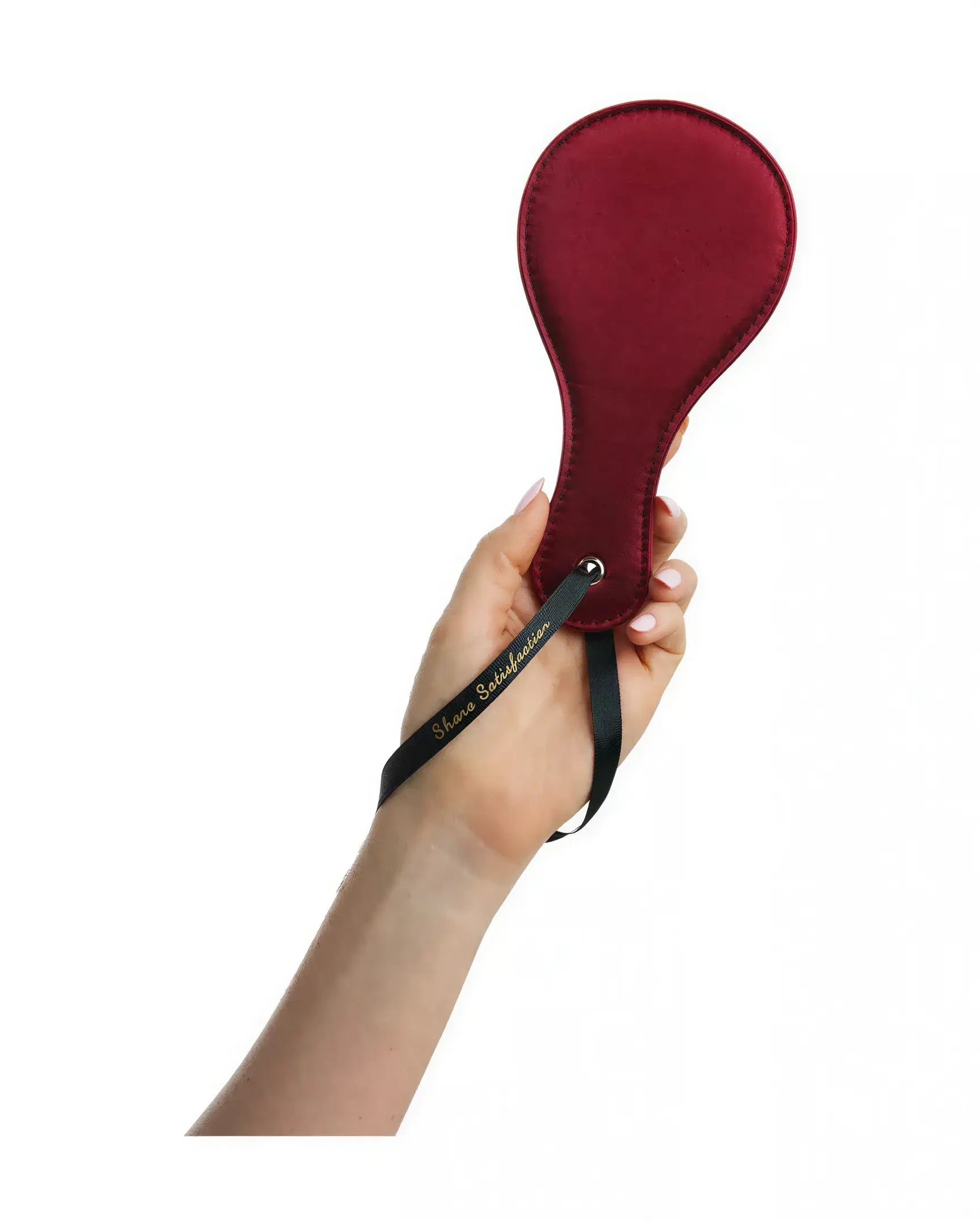Luxury paddle in red with a black wrist strap, held in a hand against a white background.