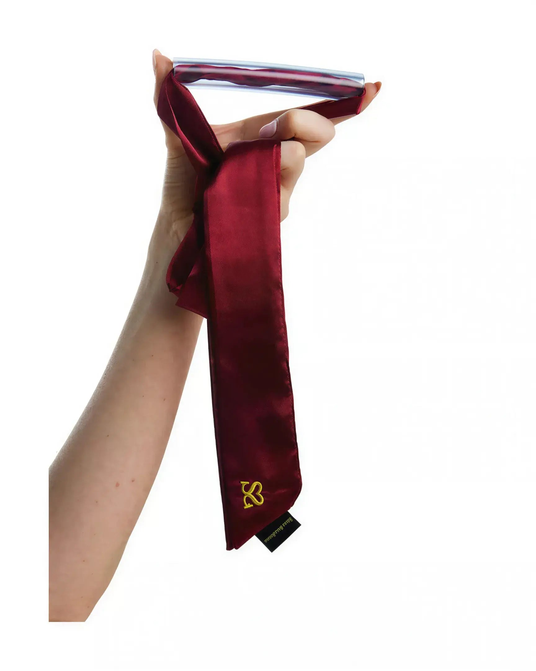Luxury bar gag in burgundy satin held by a hand, featuring a sleek design and a logo tag.