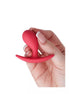 Small curved plug in vibrant red held between fingers, showcasing its smooth silicone texture and ergonomic design.