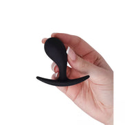 Medium curved plug held in a hand, featuring a smooth black silicone surface and a flared base for safety.