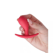 Medium curved plug in red silicone, held in a hand, showcasing its ergonomic design and smooth surface.