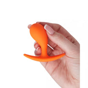 Medium curved plug in bright orange held in a hand, featuring a tapered tip and a flared base for safety.