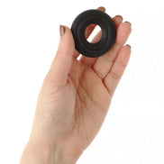 Black butter cookie cock ring held in a hand, showcasing its circular shape and textured surface.