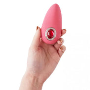 Sana Luxury Lay-On in pink held in a hand, featuring a decorative red gem and silver accents.