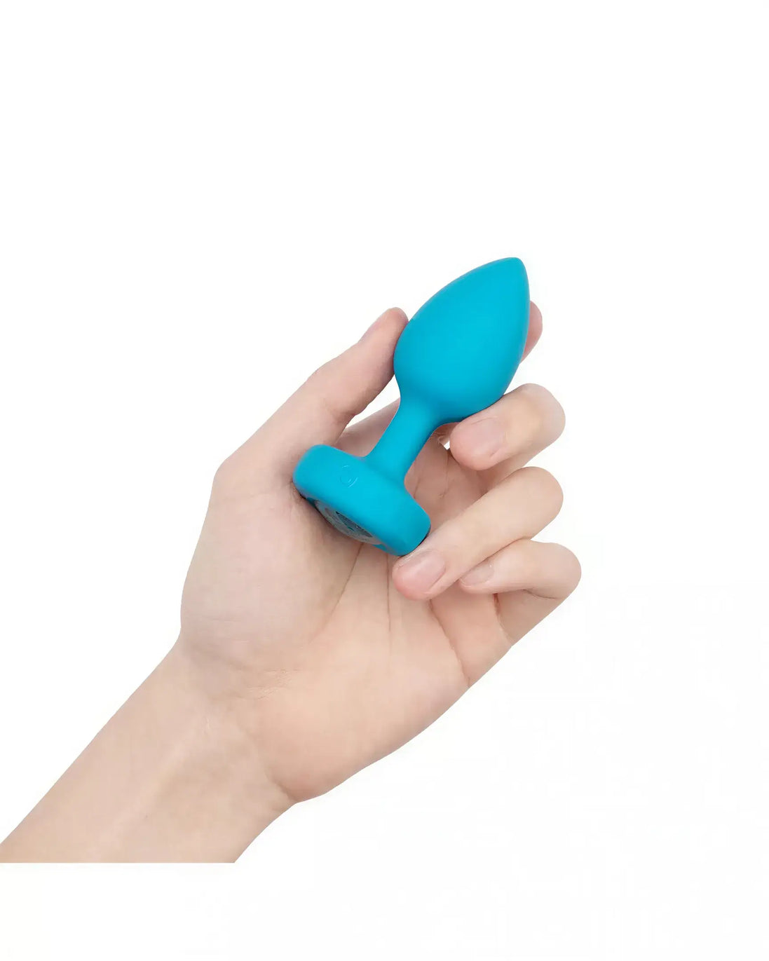 B-Vibe vibrating jewel plug in bright blue held in a hand, showcasing its tapered design and smooth surface.