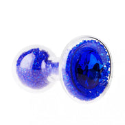 Lucent glass butt plug with a blue gem and sparkling blue crystals, featuring a clear body and rounded base.