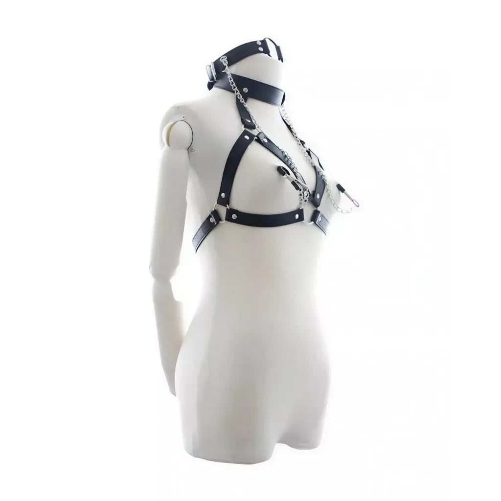 Black bondage harness with nipple clamps displayed on a mannequin, featuring silver accents and adjustable straps.