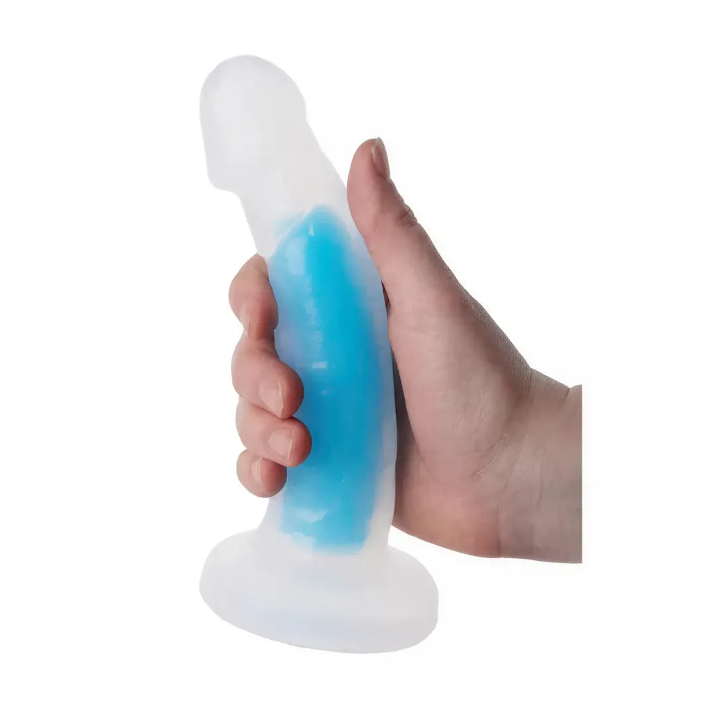 Nood Colours glow in the dark dildo, 7.5 inches, held in a hand, featuring a translucent design with blue accents.