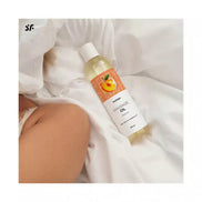Satisfyer massage oil in a 250ml bottle with a peach label, placed on white fabric.