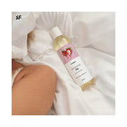 Satisfyer massage oil in a 250ml bottle with a strawberry design, placed on white fabric.