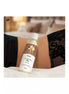 Satisfyer massage oil vanilla 250ml bottle placed on a bed with lace fabric in the background.