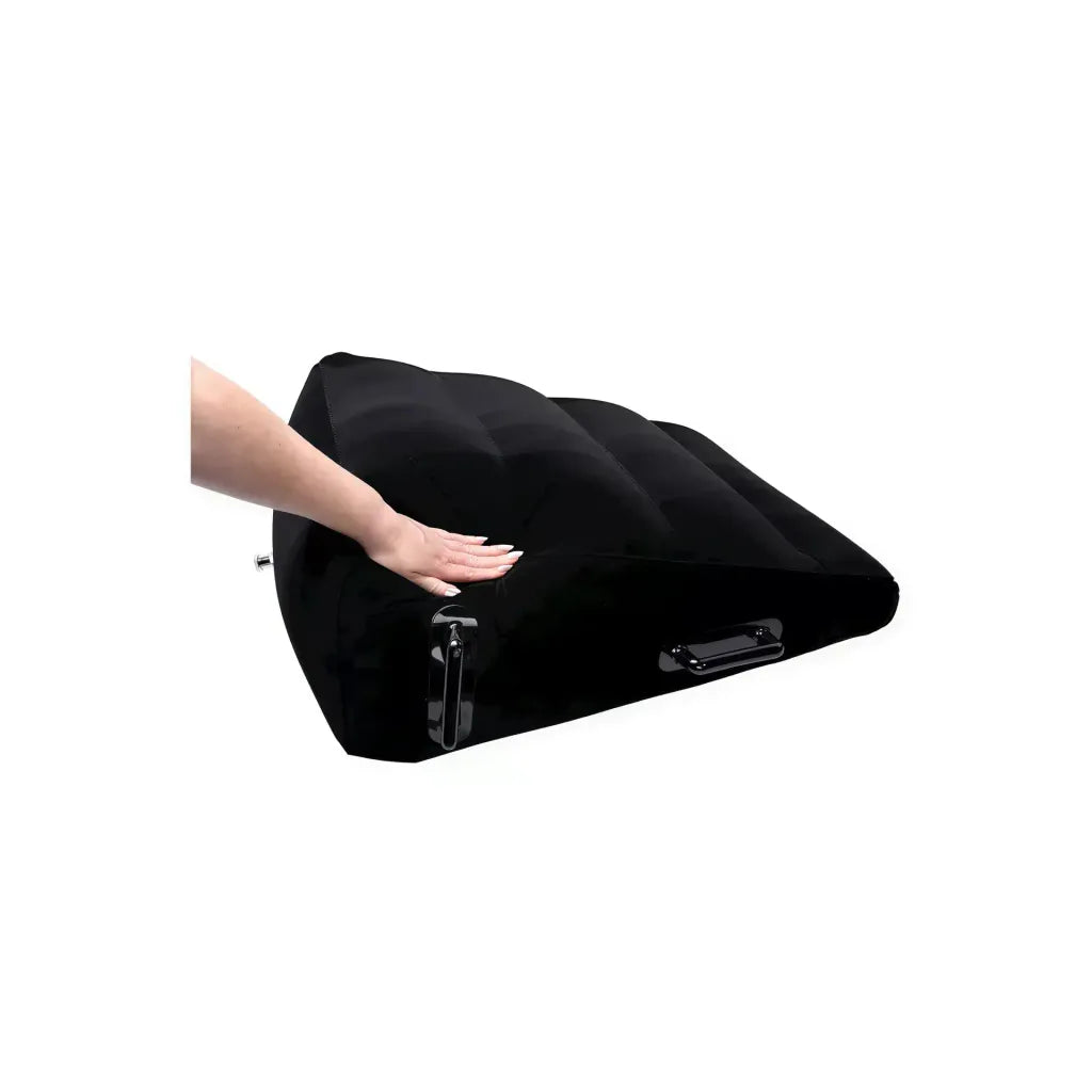 Black inflatable positioner with a hand pressing down on its surface, showcasing its texture and design.