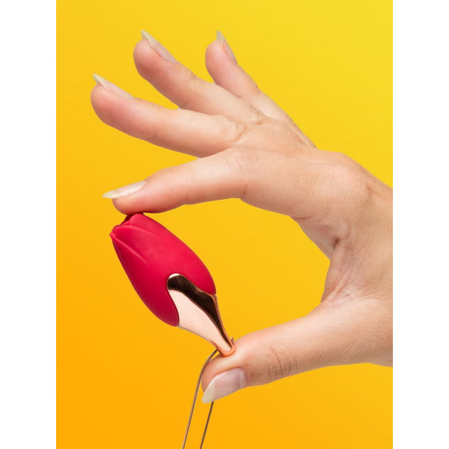 The Pleasure Company Patina necklace vibrator held in a hand, featuring a red floral design with a gold accent.